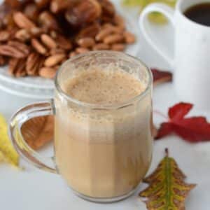 A close up image of a pumpkin spice latte in a glass cup.