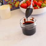 A jar of balsamic glaze with a spoon.