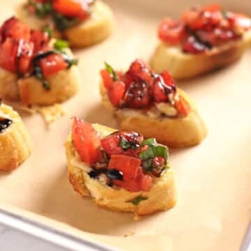 Bread slices on baking sheet topped with bruschetta.