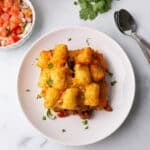 An overhead view of a white plate with a serving of tater tot casserole.