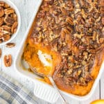 An overhead view of a cracker barrel sweet potato in a white casserole with a spoon.