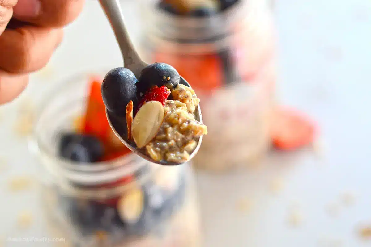 A spoon with some overnight oats with blueberries.