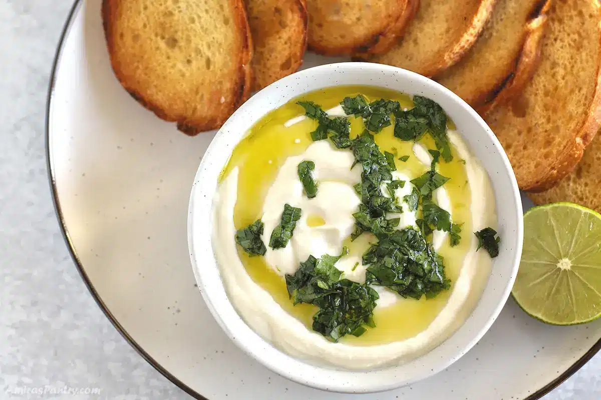A bowl of whipped ricotta with bread slices on a plate.