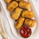 An oval serving dish with potato croquettes.