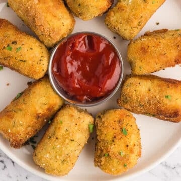 A top view of potato croquettes platter with sauce in the middle.