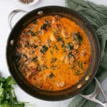 Tuscam shrimp in creamy sauce in a dark skillet with green cloth on the side.