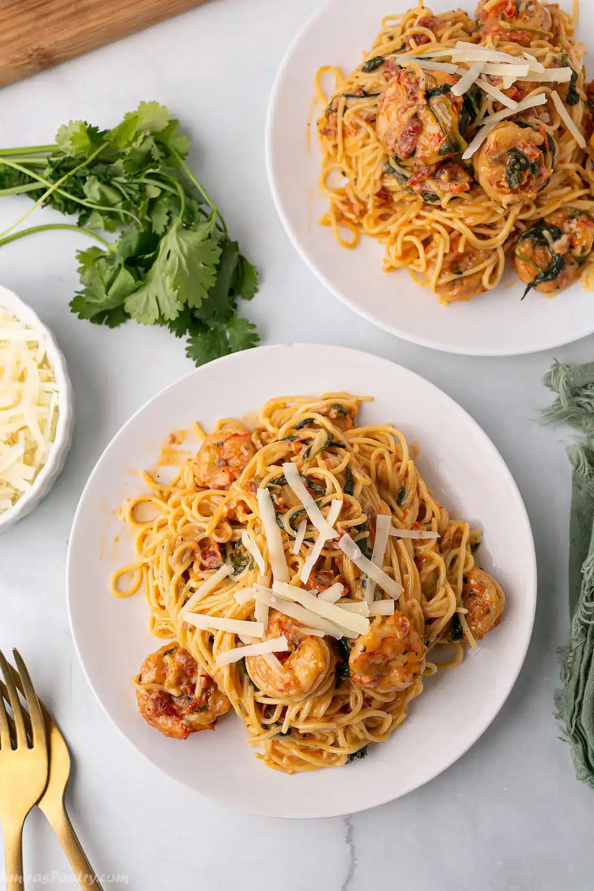 Tuscan shrimp pasta servings on white dishes.