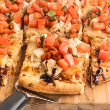 A pizza serving spoon pulling a piece of pizza out.