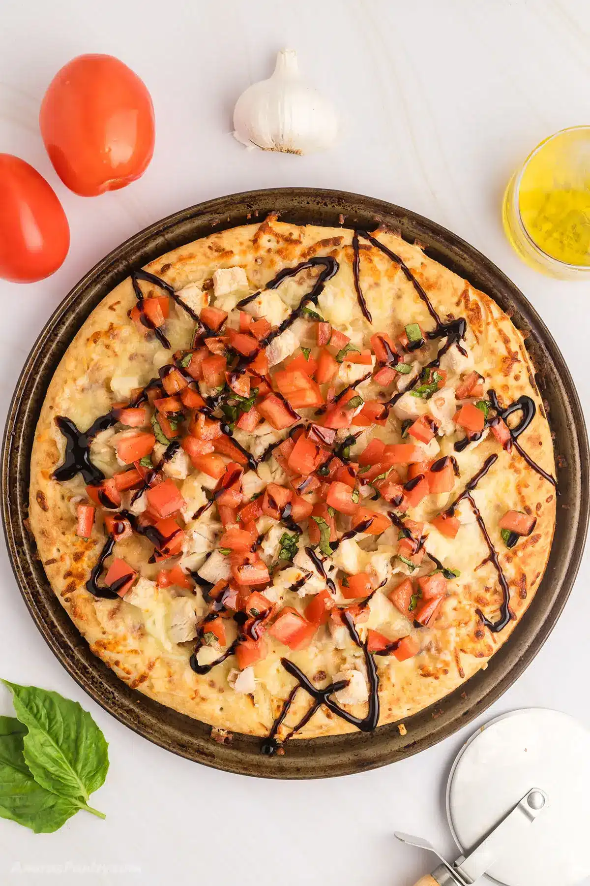 An overhead image of a bruschetta pizza on a pizza pan.