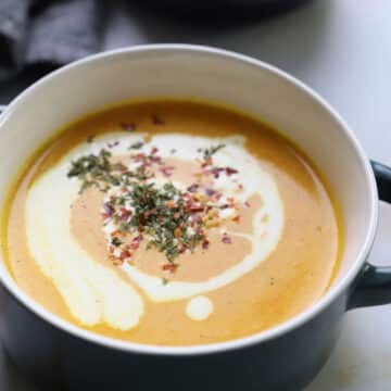 A zoomed in image of a bowl with carrot lentil soup.