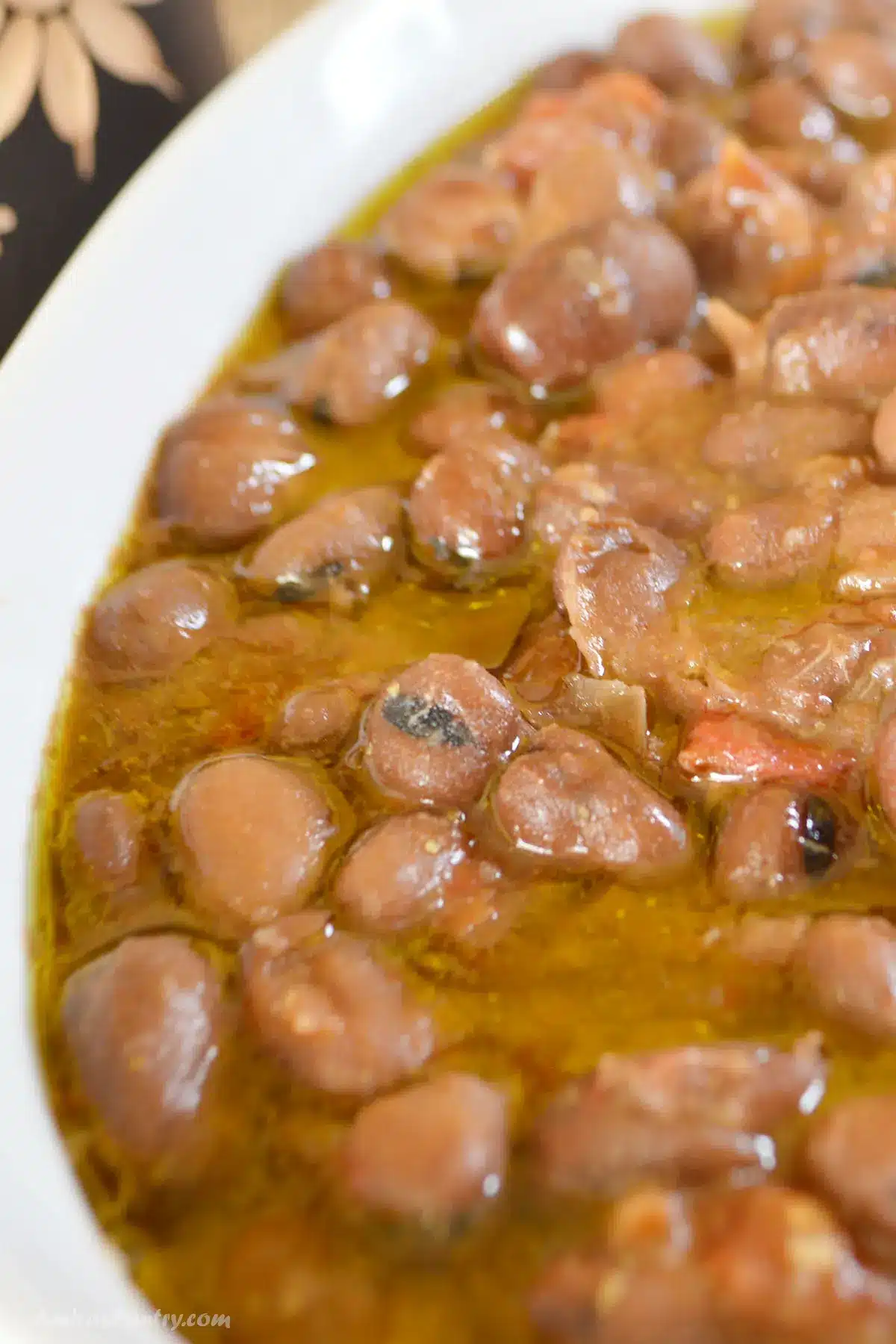 A top image of a white dish with cooked beans.