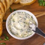 A butter knife in a bowl with garlic butter.