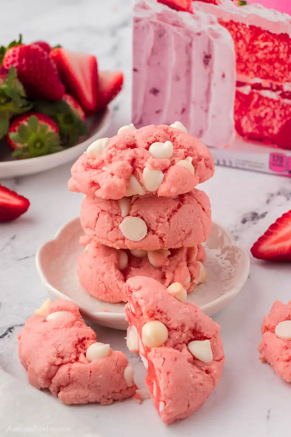 A stack of strawberry cake mix cookies with one cut in hlaf.