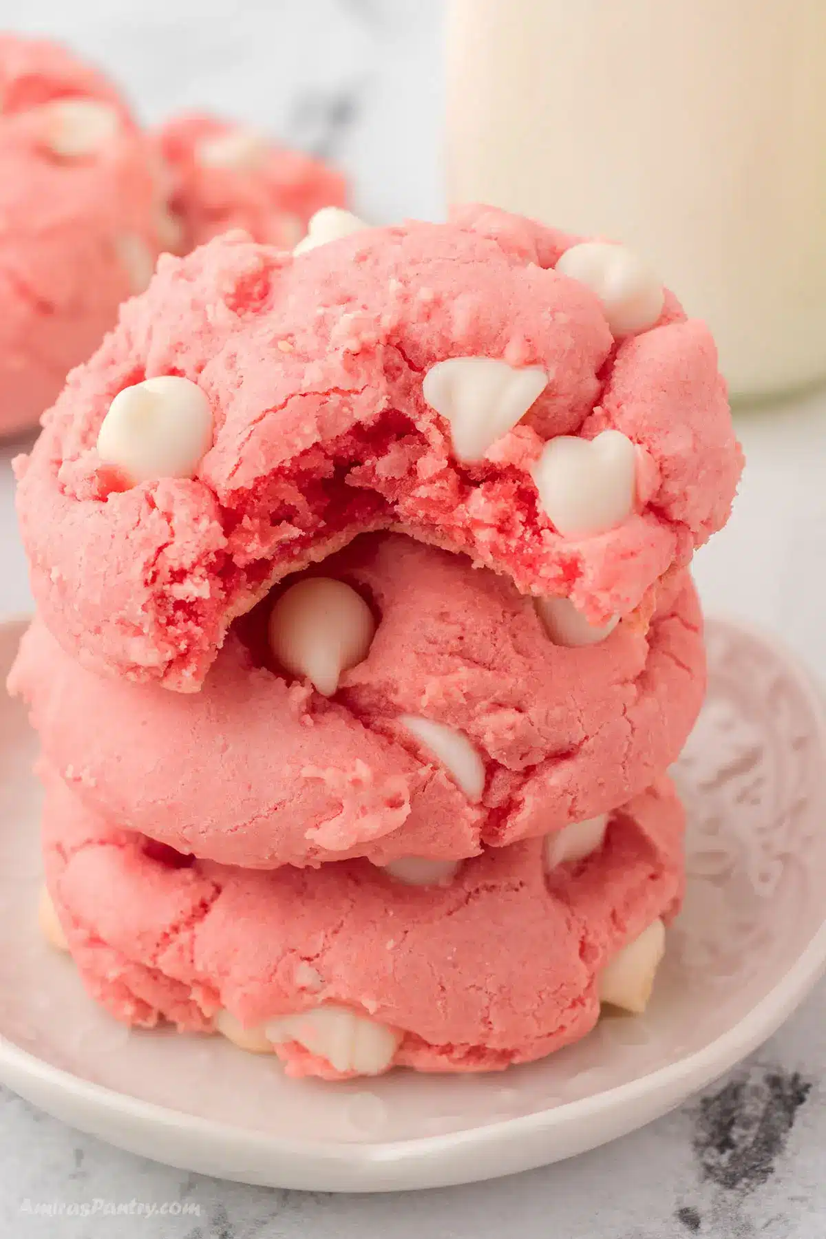 A stack of strawberry cookies with a bite taken from the top one.