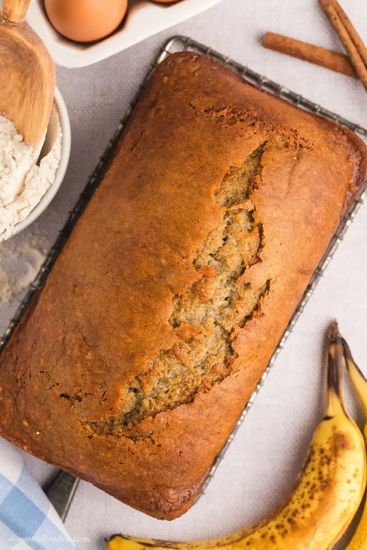 Banana bread on a counter with brown bananas on the side.