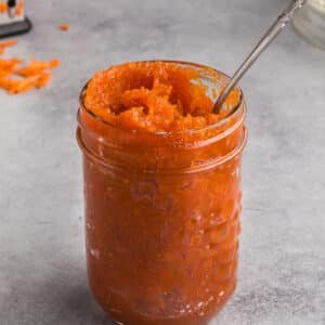 A jar of carrot jam with a spoon in it.