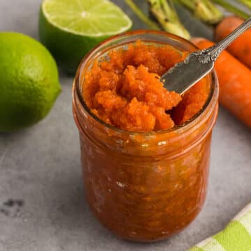 A jar of carrot jam with a spoon in it.