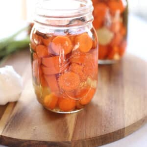 A close up image of a mason jar with pickled carrots.