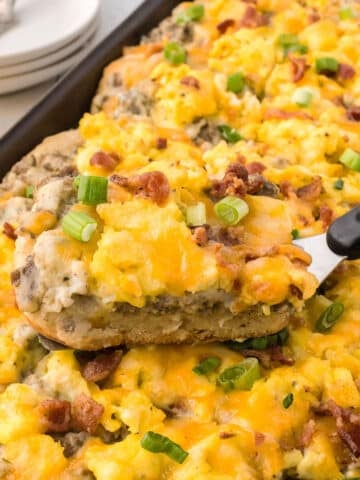 A close up image on a serving spatula with a piece of breakfast pizza.