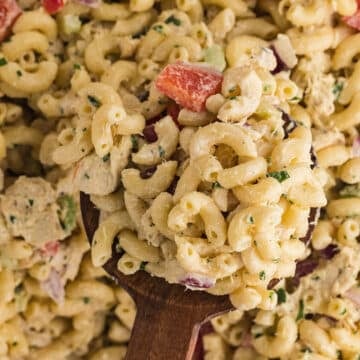 A wooden spoon scooping some macaroni salad.