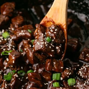 A close up look at honey garlic steak bites in a wooden spoon.