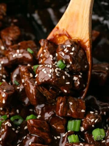 A close up look at honey garlic steak bites in a wooden spoon.