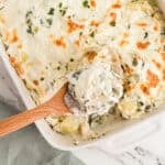 An overhead image of a chicken casserole with a wooden spoon in it.