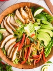 A close up image of a wooden bowl with fajita salad.