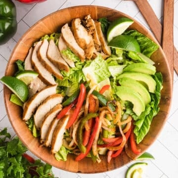 A close up image of a wooden bowl with fajita salad.