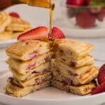 A stack of pancakes cut to show texture with syrup poured on top.