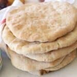 A stack of Taboon bread with a white towel in the back.