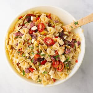 A white bowl with Italian pasta salad garnished with parsley.