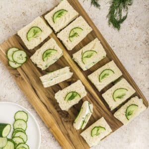 An overhead image of cucumber sandwiches on a wooden board.