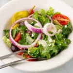 A close up image of a white salad bowl with copycat for Panera Bread Greek salad.