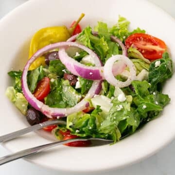 A close up image of a white salad bowl with copycat for Panera Bread Greek salad.