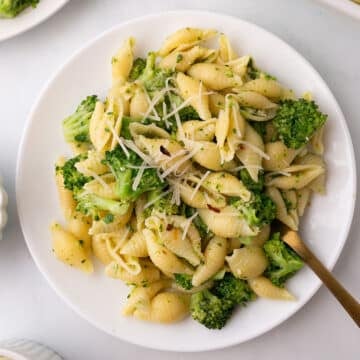 A dinner plate with pasta side dish with a spoon.