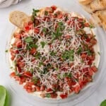 An overhead image of a platter with bruschetta dip and bread slices on the side.