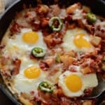 A cast iron skillet of potato shakshuka with a spoon.