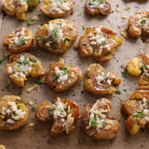 Smashed potatoes on a metal baking sheet.