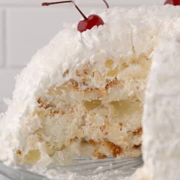 A side view of a snowball cake with a slice taken from it.