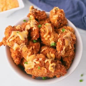 An overhead image of a bowl with fried chicken bites drizzled in bang bang sauce.