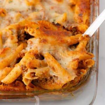 A spoon scooping some pasta from the casserole dish.