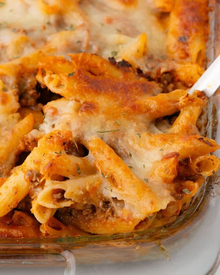 A spoon scooping some pasta from the casserole dish.