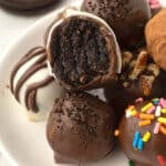 A pile of oreo balls decorated with chocolate on a white platter.