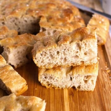 A stack of focaccia slices on a wooden board.