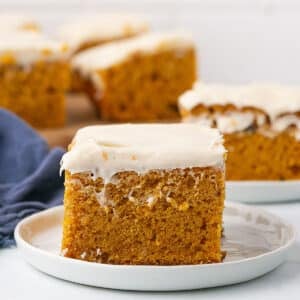 A zoom in image on a pumokin bar on a white plate with cream cheese frosting.