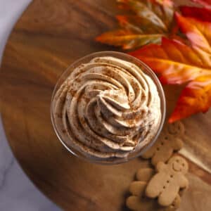 An overhead image of pumpkin whipped cream on a glass placed on a wooden board.