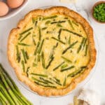 An overhead image of asparagus quiche on a white countertop.
