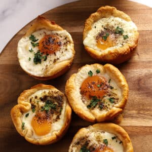 Biscuits with eggs in the middle on a wooden board.