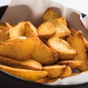 A close up image on a plate with potato wedges.